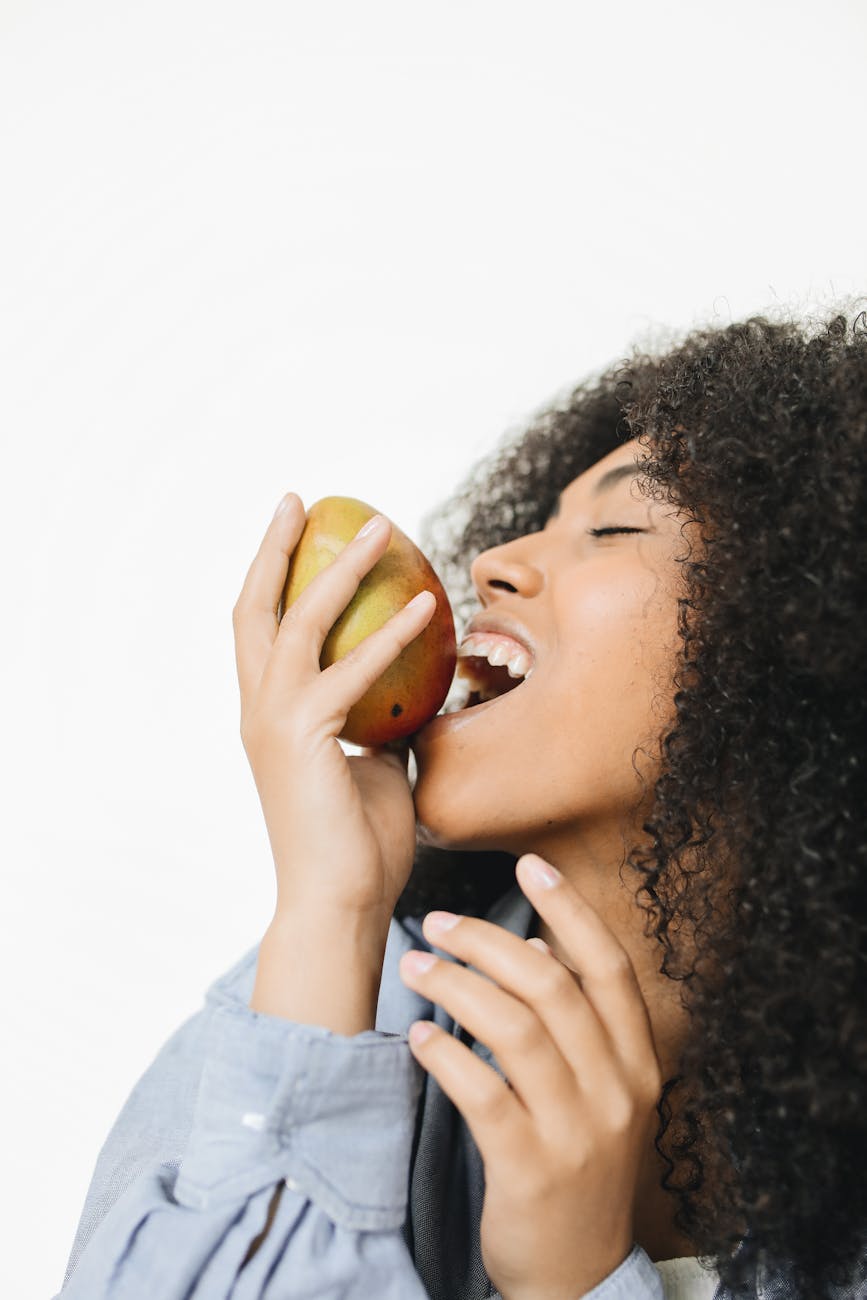 a woman biting a mango